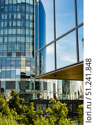 Modern Architectural Reflection: A Blend of Glass Facades and Lush Greenery Capturing Urban Life and Natural Beauty Coexisting in Perfect Harmony. Стоковое фото, фотограф Владимир Федоров / Фотобанк Лори