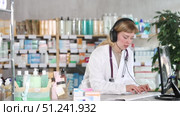 Female pharmacist in headphones is talking with patient - checking data on a computer. Стоковое видео, видеограф Яков Филимонов / Фотобанк Лори