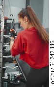 Woman in sports gloves pulling cable machine during workout at gym. Concept of strength training, dedication and building healthy body through discipline and motivation. Стоковое видео, видеограф Енваев Андрей / Фотобанк Лори