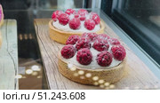 An assortment of Delicious Raspberry Tarts Beautifully Displayed in a Cozy Bakery. Delightful elegant raspberry tarts exquisitely topped with rich whipped cream and lightly dusted with powdered sugar. Стоковое видео, видеограф worker / Фотобанк Лори