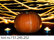 Orange pumpkin and two lighted tea candles on background of fire lines. Halloween concept. Стоковое фото, фотограф Зарифа Арсланова / Фотобанк Лори