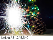Fir cone with Bengal light flash on background christmas tree with garland lights. Selective focus. Стоковое фото, фотограф Зарифа Арсланова / Фотобанк Лори