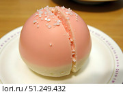 Traditional Japanese dessert, mochi cake in thin pink rice dough on a pink background with pink filling, cut, open space. Стоковое AI-изображение, AI-художник Ирина Старикова / Фотобанк Лори