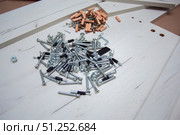 Furniture fasteners are poured out in a pile on furniture parts. Стоковое фото, фотограф Екатерина Кузнецова / Фотобанк Лори