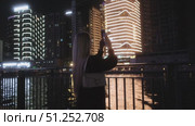 A woman captures urban beauty at night, showcasing stunning scenes. Стоковое видео, видеограф Cantemir Dumitru / Фотобанк Лори