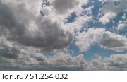 A time-lapse shot of a bright blue sky covered with large fluffy white cumulus clouds casting soft shadows in the bright daylight. Стоковое видео, видеограф Олег Альбертович Потаскуев / Фотобанк Лори