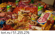 Colorful candy, sugary drinks and snacks overflowing on table, representing unhealthy eating habits. Стоковое фото, фотограф David Kashakhi / Фотобанк Лори