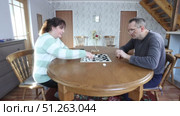 Checkers played by mature husband and wife at dining table concentrating on game pieces and enjoying quiet moment together at home. Стоковое видео, видеограф Владимир Григорьев / Фотобанк Лори