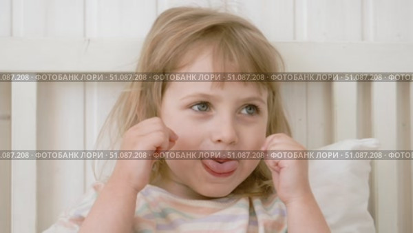 4 years girl joking, sticking tongue out with silly expression. Child making face. Funny foolishness portrait of little kid doing crazy comical gesture among a white wall. Closeup face. Low contrast. Стоковое видео, видеограф Марина Демидюк / Фотобанк Лори