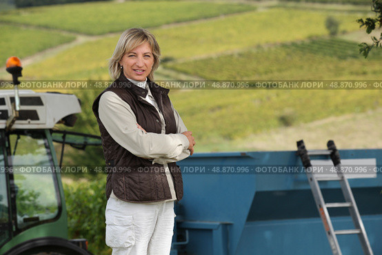 45 years old woman in front of a tractor and vines. Стоковое фото, агентство Ingram Publishing / Фотобанк Лори