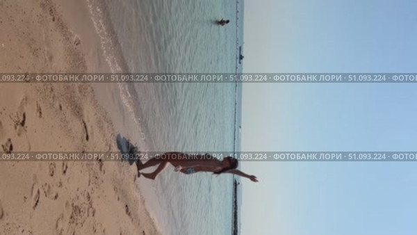 A 50-year-old European woman in a swimsuit walks along the beach in Doha, Qatar. Стоковое видео, видеограф IRYNA ZAKHARANKA / Фотобанк Лори