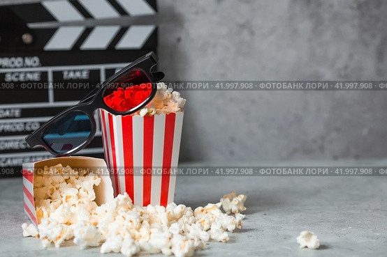 A banner for the film industry. A movie date. A movie camera, 3D glasses, popcorn in striped cups on a stylish concrete gray background. The premiere of the film. (2024 год). Стоковое фото, фотограф Photojuli / Фотобанк Лори