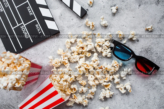 A banner for the film industry. A movie date. A movie camera, 3D glasses, popcorn in striped cups on a stylish concrete gray background. The premiere of the film. (2024 год). Стоковое фото, фотограф Photojuli / Фотобанк Лори