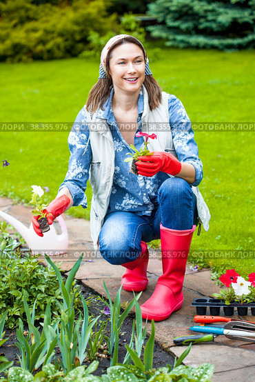 A beautiful woman in the garden is planting flowers in a flower bed. Стоковое фото, фотограф Astroid / Фотобанк Лори