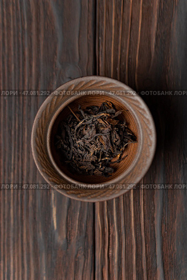 A Bowl Filled with Dried Black Tea Leaves Placed on a Rustic Wooden Table Surface. Стоковое фото, фотограф David Kashakhi / Фотобанк Лори