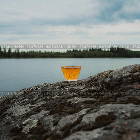 A calming and tranquil waterside scene featuring a refreshing beverage in the heart of nature. Стоковое фото, фотограф David Kashakhi / Фотобанк Лори