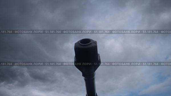 A cannon stands ready to unleash destruction against a backdrop of dark, swirling clouds, symbolizing the turmoil of war in Russia. The tension is palpable in the air. Стоковое фото, фотограф Громов Александр / Фотобанк Лори