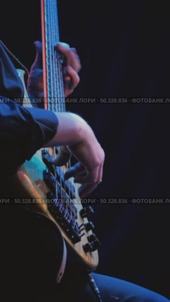 A close-up of a musician's hands skillfully playing a bass guitar. The strings vibrate under his fingers, blue lighting illuminates the bassist. Jazz band on stage. Стоковое видео, видеограф Воловодов Владимир / Фотобанк Лори