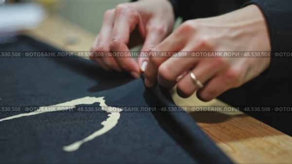 A close-up of a woman's hands sewing a black cloth banner, her fingers trembling slightly as she prepares for the Ashura process. Стоковое AI-видео, аниматор Sergey Grishin / Фотобанк Лори