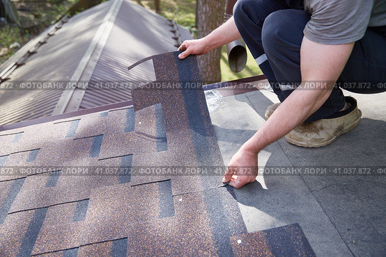 A close-up of the master's hands on the roof mounts flexible tiles. Стоковое фото, фотограф Кутина Татьяна / Фотобанк Лори