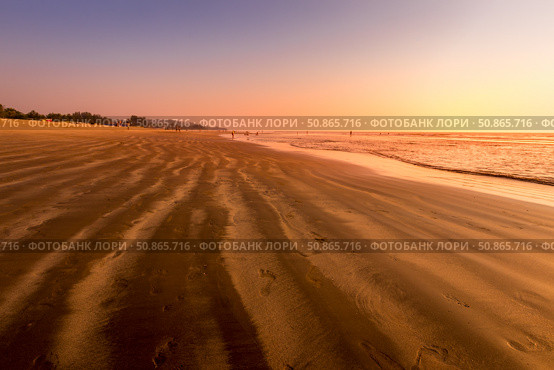 A colorful sunset or sunrise on the seaside with a sandy beach with impurities of volcanic ash. Mandrem, Goa, India. (2018 год). Стоковое фото, фотограф Емельянов Евгений Викторович / Фотобанк Лори