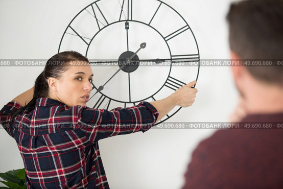 a couple hanging a clock on the wall. Стоковое фото, агентство Ingram Publishing / Фотобанк Лори