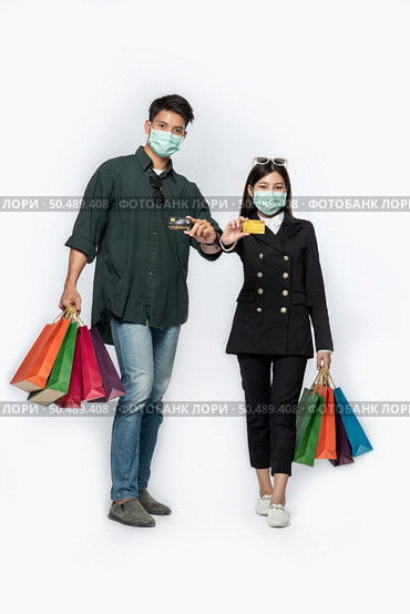 A couple of men and women wore masks and carried lots of paper bags to shop. Стоковое фото, агентство Ingram Publishing / Фотобанк Лори