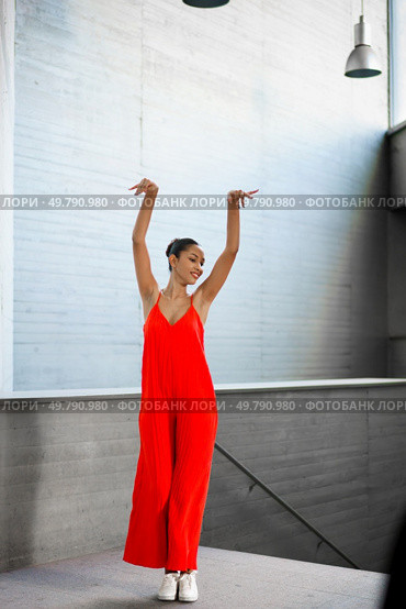 A dancer in a vivid red outfit strikes a captivating pose, showcasing her talent in a contemporary setting, embodying grace and dynamic movement while radiating effortless energy that draws all eyes. An Elegant Dancer Dressed in Vibrant Red Attire Poses Beautifully in a Modern Interior. Стоковое фото, агентство Ingram Publishing / Фотобанк Лори