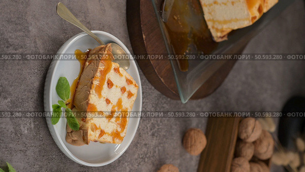 A delectable slice of molotov pudding, generously drizzled with caramel and garnished with fresh mint, presented on a small, elegant plate with a spoon. Стоковое фото, агентство Ingram Publishing / Фотобанк Лори