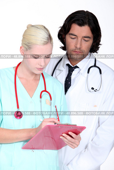 a doctor and a nurse looking seriously a paper. Стоковое фото, агентство Ingram Publishing / Фотобанк Лори