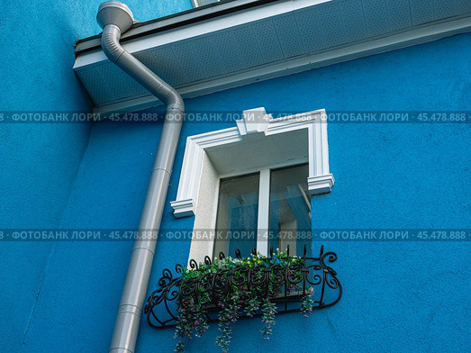 A drainpipe outside a building with blue walls. A drainage system designed to drain meltwater and rainwater. Drainage system to protect against the negative effects of precipitation. Стоковое фото, фотограф Эдуард Белкин / Фотобанк Лори