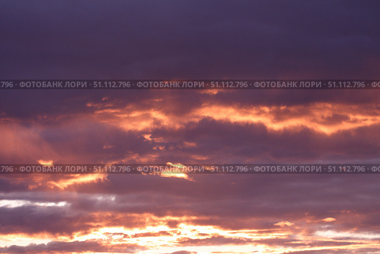 A dramatic sunset paints the sky with shades of purple and orange, highlighting the clouds. Concept of: Atmospheric beauty. Стоковое фото, фотограф Ольга Петрова-Апостолова / Фотобанк Лори