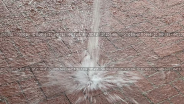 A dynamic water splash captured on a brick pavement, showing droplets in mid-air as they hit the ground. The image highlights the impact and texture of both water and surface. Стоковое видео, видеограф Marina Gabdullina / Фотобанк Лори