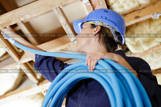 a female builder conecting cables. Стоковое фото, агентство Ingram Publishing / Фотобанк Лори