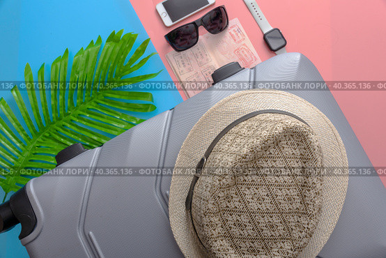 A flat with a gray tourist suitcase, a smartphone, and glasses on a pink-blue background. Стоковое фото, фотограф Ярославский Максим / Фотобанк Лори