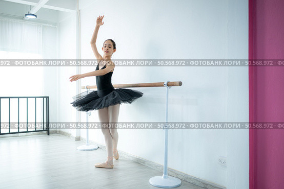 A girl ballet student practices ballet dancing at home with a white background. Стоковое фото, агентство Ingram Publishing / Фотобанк Лори
