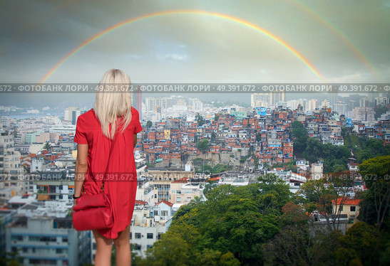 A girl in a red dress looks at the rainbow over the favelas in RIO. Стоковое фото, агентство Ingram Publishing / Фотобанк Лори