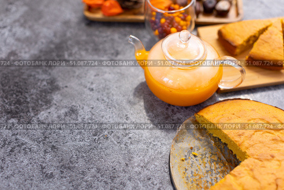 A glass teapot with a beautiful orange pie drink on a gray table. Стоковое фото, фотограф Alexandra Aleroewa / Фотобанк Лори