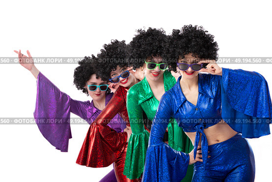 A group of girls in colorful flared suits and afro wigs pose against a white background. Disco style from the eighties or seventies. Стоковое фото, фотограф Лазаренко Светлана / Фотобанк Лори