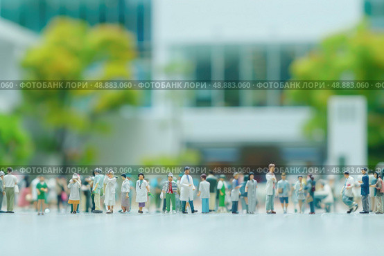 A group of miniature people stand on a city street, their tiny forms dwarfed by the towering buildings and lush greenery in the background. Стоковое AI-изображение, AI-художник Данила Большаков / Фотобанк Лори