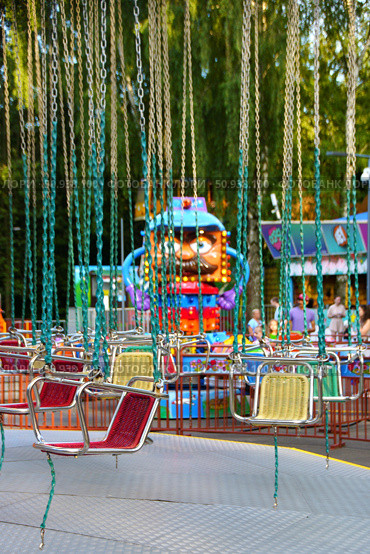 A group of swings is suspended from a chain, with one blue-red in the middle. Russia. Moscow. 25.07.25. Редакционное фото, фотограф Ярославский Максим / Фотобанк Лори