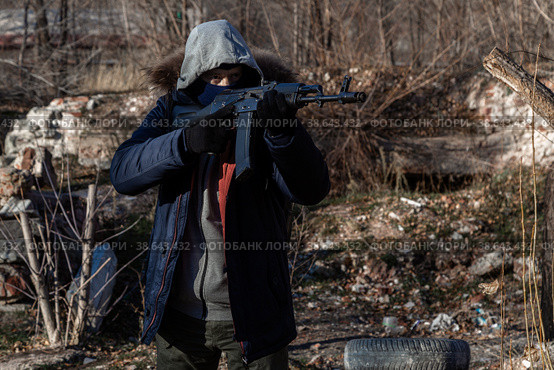 A grown man wearing a mask, wearing a jacket with a hood, wearing military pants, wearing gloves aims at a weapon. Стоковое фото, фотограф Владимир Арсентьев / Фотобанк Лори