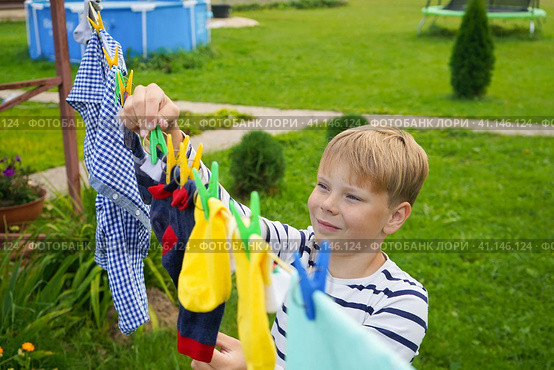 A happy caucasian 9 years boy helps her mother to hang up clothes. Development of fine motor skills through household activities. Selective focus. Стоковое фото, фотограф Ирина Старикова / Фотобанк Лори