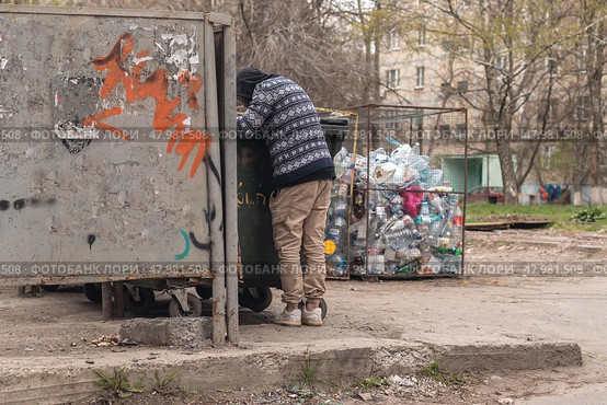 A homeless man digs through garbage in search of food. Стоковое фото, фотограф Михаил Яковлев / Фотобанк Лори
