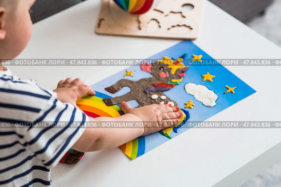 A little boy is playing with plasticine. Fine motor skills-developing games for children. The kid makes a horse. Useful games for child development. Стоковое фото, фотограф Photojuli / Фотобанк Лори