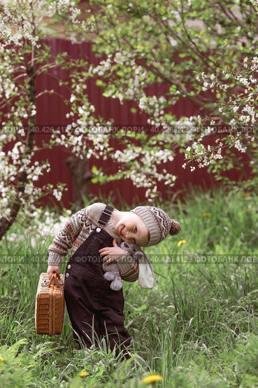A little boy of 4 years old outdoors with a suitcase and a stuffed rabbit goes on a journey. A beautiful portrait of a child playing on the street. Стоковое фото, фотограф Photojuli / Фотобанк Лори