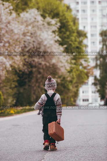 A little boy of 4 years old outdoors with a suitcase and a stuffed rabbit goes on a journey. A beautiful portrait of a child playing on the street. Стоковое фото, фотограф Photojuli / Фотобанк Лори