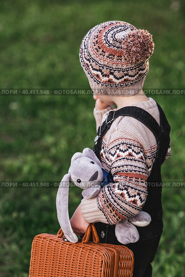 A little boy of 4 years old outdoors with a suitcase and a stuffed rabbit goes on a journey. A beautiful portrait of a child playing on the street. Стоковое фото, фотограф Photojuli / Фотобанк Лори
