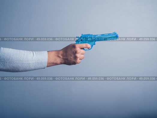 A male hand is holding a blue water pistol and is aiming it. Стоковое фото, агентство Ingram Publishing / Фотобанк Лори