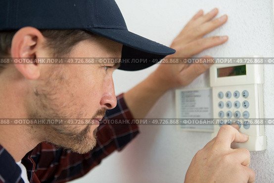 a male technician repairing intercom. Стоковое фото, агентство Ingram Publishing / Фотобанк Лори